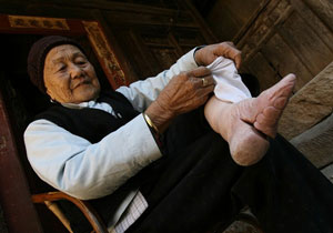 Uma mulher mostra como tinham de amarrar os pés antes da Revolução, para os manterem muito pequenos