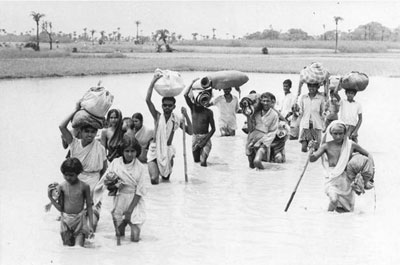 Camponeses em fuga deixam para trás as suas casas e aldeias e atravessam a pé um rio, com água até aos joelhos